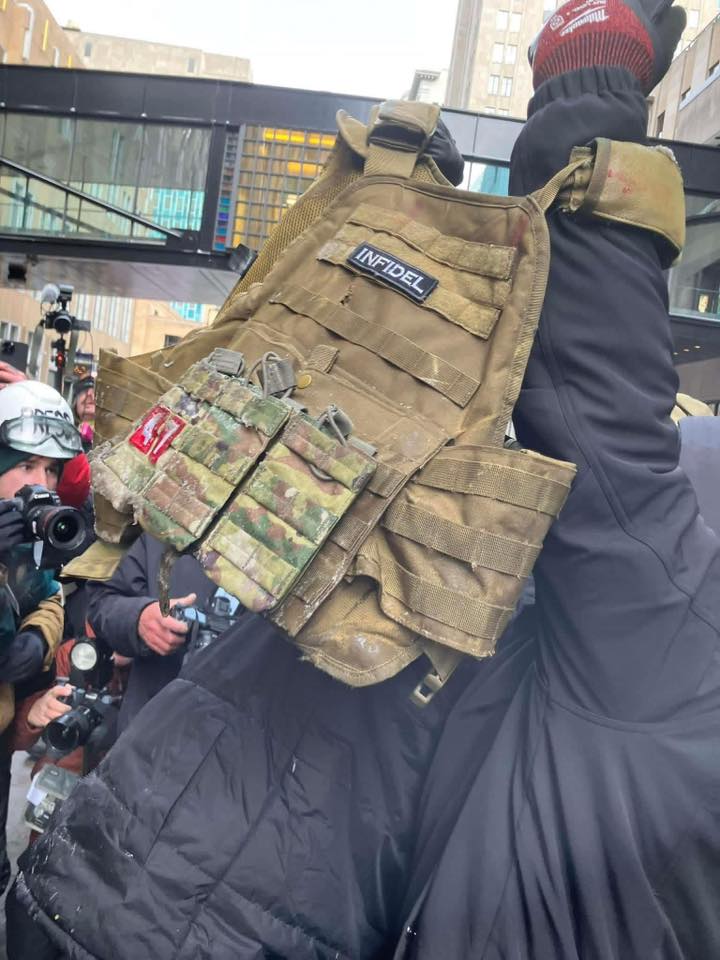 Member of a victorious crowd hold up the captured plate carrier of a far right militant