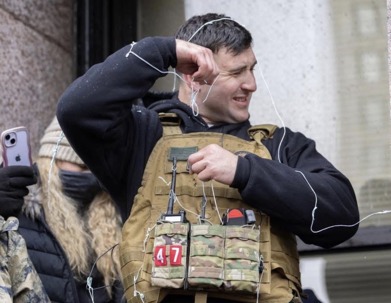 A far right militant in a plate carrier is sprayed with silly string